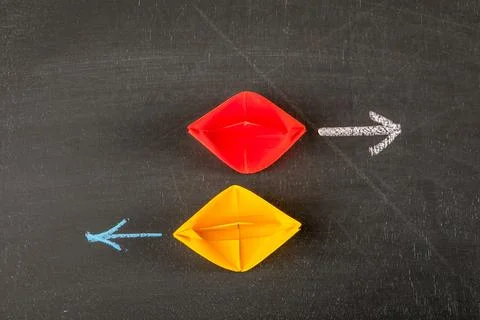 Opposite Direction Strategy Concept With Red and Yellow Paper Boats and Arrow 스톡 사진