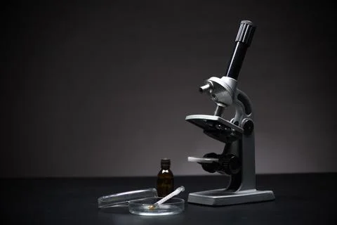 Optical microscope on a black background, petri dish and syringe for injectio Stock Photos