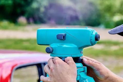 Optical surveying device is positioned on sturdy tripod while user rotates .. 스톡 사진
