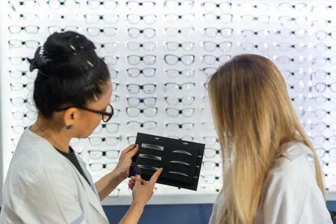 Optician explaining lens thickness options to customer 스톡 사진