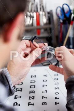 Optician fixing lens on frame at workshop Stock Photos