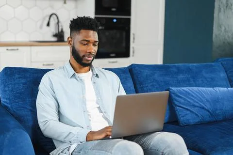 Optimistic confident dark-haired handsome guy using laptop for work. Multiracial Stock Photos