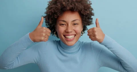 Optimistic dark skinned woman makes thumbs up gives approval shows excellent Stock Footage 142328753