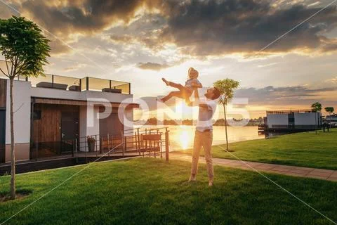Optimistic father throwing laughing daughter during evening Stock Photos