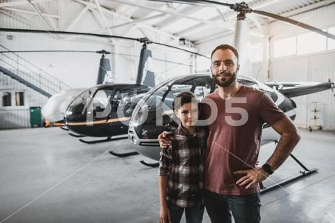 Optimistic male hugging satisfied kid opposite rotorcrafts Stock Photos