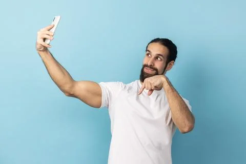 Optimistic man broadcasting livestream, pointing finger down, subscribe. Stock Photos