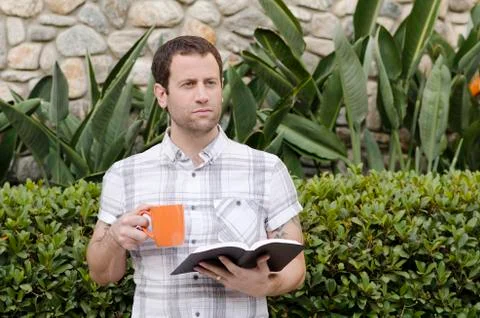 Optimistic man looking out with book and coffee mug in hand. Stock Photos