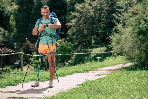 Optimistic motivated man with prosthesis trying up Nordic walking Stock Photos