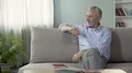 Optimistic senior male sitting on sofa and planning his vacation, retirement 4k or 4k+ Resolution