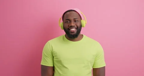 Optimistic smiling relaxed guy with dark skin wears casual t shirt wears stereo Stock Footage 149915881