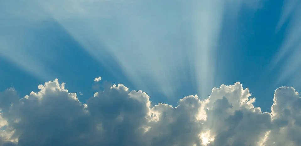 Optimistic sunset rays behind the clouds. Glow in the sky. Symbol of light. B Stock Photos