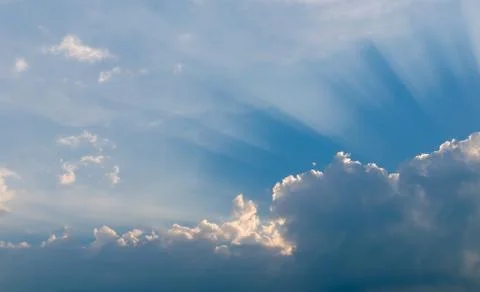 Optimistic sunset rays behind the clouds. Glow in the sky. Symbol of light. B Stock Photos