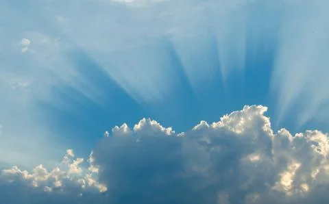 Optimistic sunset rays behind the clouds. Glow in the sky. Symbol of light. B Stock Photos