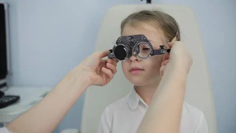 Optometrist fitting test glasses on young patient Stock Footage 320186179