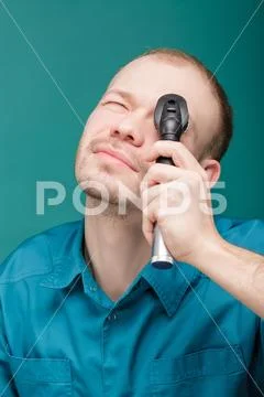 Optometrist with ophthalmoscope, instrument to look into eyes by doctor on blue Stock Photos