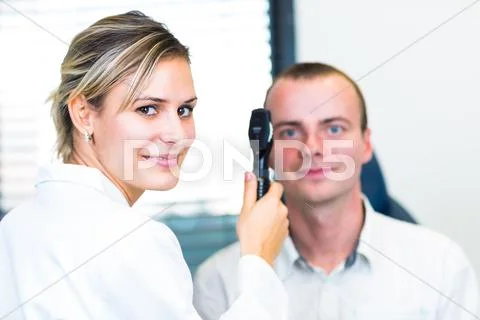 Optometry concept - handsome young man having his eyes examined Stock Photos