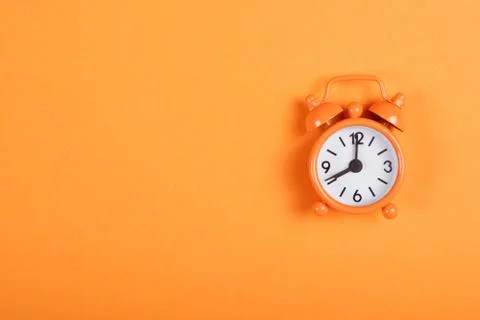 Orange alarm clock on background of the same tone. Stock Photos