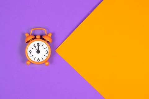 Orange alarm clock on colored background. Stock Photos