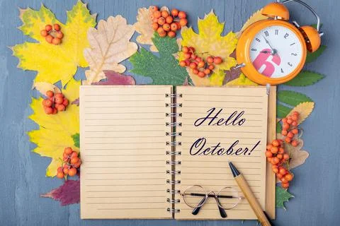Orange alarm clock, craft notepad with the words HELLO OCTOBER, pen and glass Foto stock