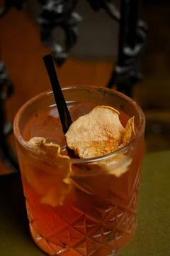 Orange alcoholic cocktail with ice on a stack of old books and dark backgroun Stock Photos