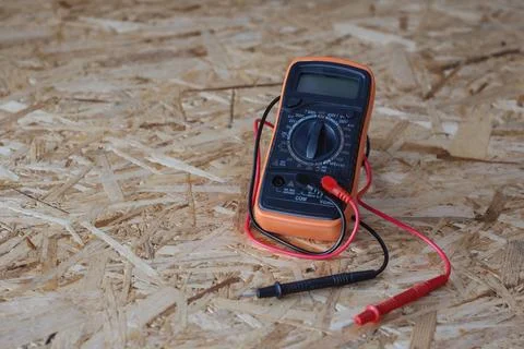 Orange and black digital multimeter with red and black test leads placed on.. Stock Photos