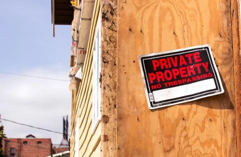 Orange and Black Private Property No Trespassing Sign posted on Wooden Panel Stock Photos