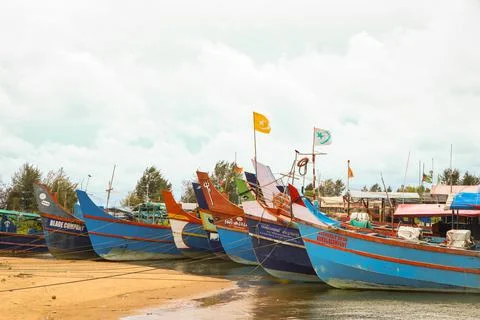 Orange and blue fishing boats lined up in a harbor Stock Photos