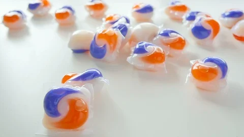 Orange and Blue Tide Laundry Detergent Pods Dropping in a Pile in Slow Motion Stock Footage 85989183