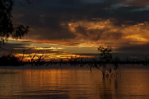 Orange and gray clouds of sunset over inland lake Stock Photos