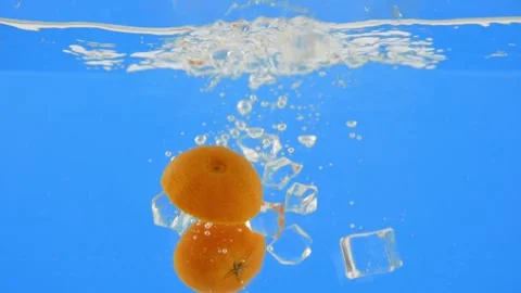 Orange and ice cubes falling into a water isolated on blue background Stock-Footage 153479405