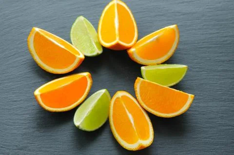 Orange and lime sliced segments on black slate stone. Vitamin concept Stock Photos