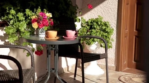 Orange and pink cups with coffee or tea stand on the table on the porch of the Stock Footage 149669388