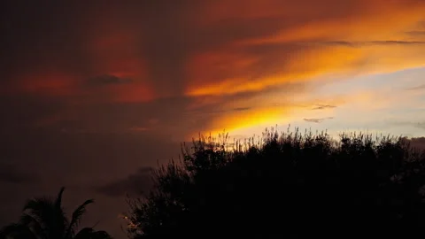 Orange and red clouds during sunset with grass in the foreground Stock Footage 268734827