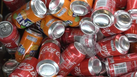 Orange and red coloured soft drink cans lie in heap on shelf Video stock 121835587