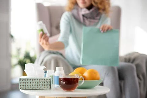 Orange and tea standing on the table while woman having flu Stock Photos