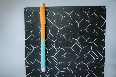 Orange and turquoise gradient pen placed vertically on a black. 库存照片