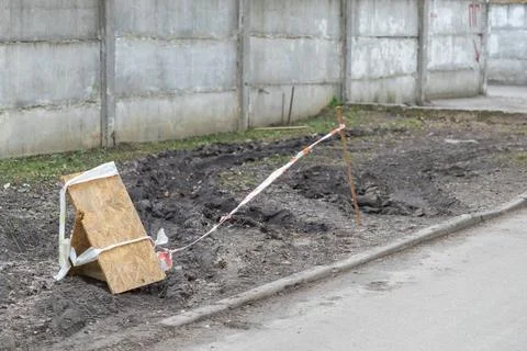 Orange and white caution tape barrier surrounding a muddy patch of ground n.. Stockfoto's