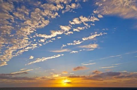 Orange and white clouds in a sunset over the ocean 写真素材