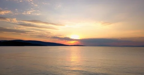Orange and yellow colored sunset with clouds over the sea Stock Footage 107983674