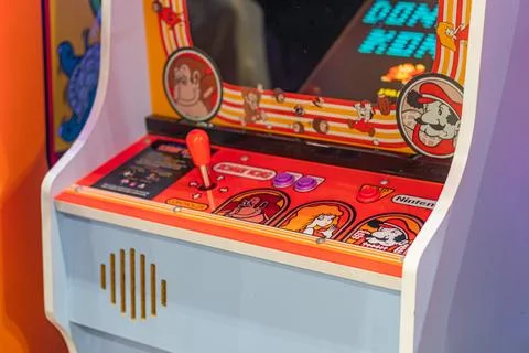 Orange arcade machine with a central button and joystick, featuring a color.. Stock Photos