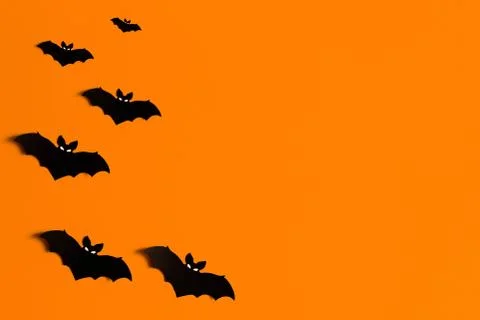 Orange background with a flock of black paper bats for Halloween, black paper Stock Illustration