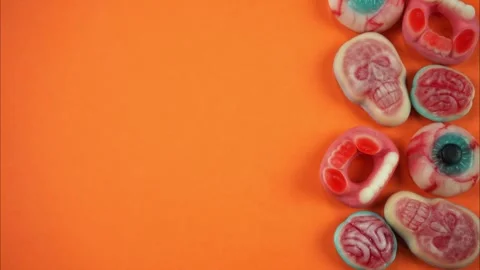 Orange background on one side of which Halloween candies appear. Stop Motion Stock Footage 253816853