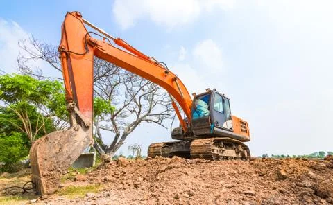 The orange backhoe is on the ground. Stock Photos