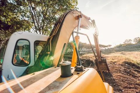 The orange backhoe is on the ground with sunset. Stock Photos