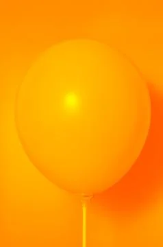 Orange balloon on orange background with shadow. Side glare. Stock Photos