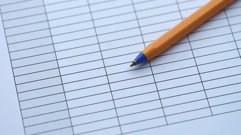 An orange ballpoint pen lying on a blank paper table grid document. Stock Footage 337262182