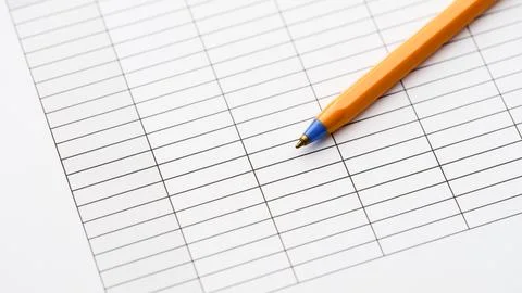 An orange ballpoint pen lying on a blank paper table grid document. Close up. Stock Photos