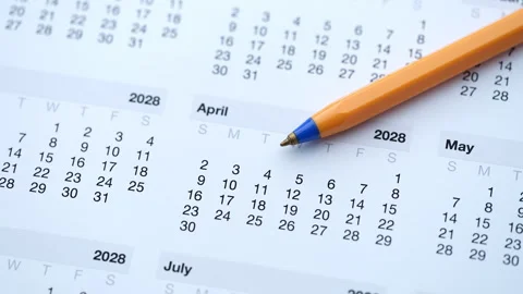 An orange ballpoint pen resting on a printed paper calendar. Stock Footage 337904557