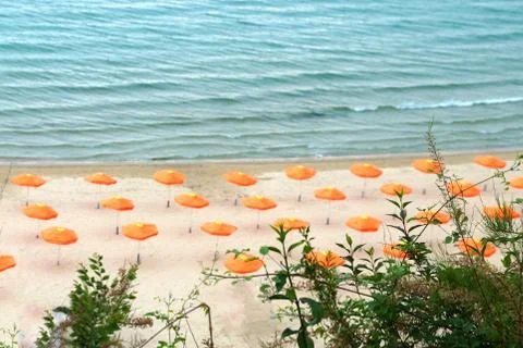 Orange beach umbrellas on an empty beach on a background of the sea Stock Photos