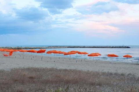 Orange beach umbrellas on an empty beach on a background of the sea Stock Photos